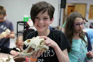 Young girl holding an animal skull and smiling