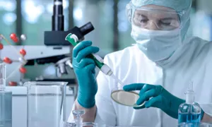person in lab in mask and gloves working with petri dish