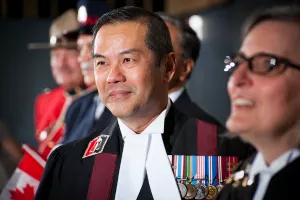 judge albert wong wearing military medals and robes with an RCMP officer in the background