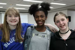 Three teen girls standing together and smiling at the camera