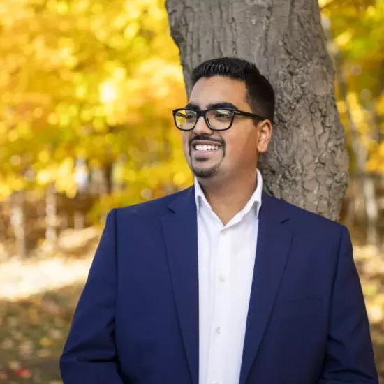 Amit Dalaya on UTM Campus standing smiling in front of a tree with yellow fall leaves