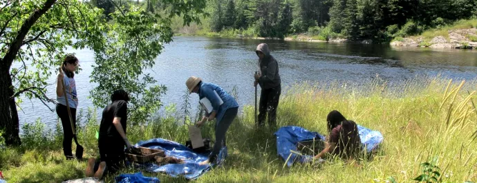a group of people working outside on a sunny summer day by a lake