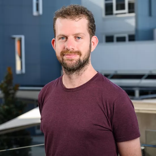 A portrait of Dr Brendan Keough, a young brown-haired professor in a t-shirt