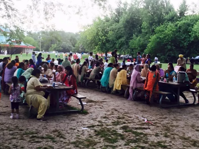 Image of ladies siting at picnic table wearing their cultural clothing. 