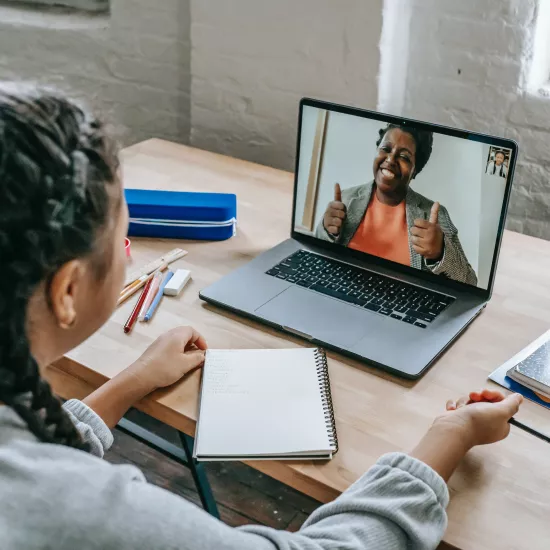 Ethnic girl having video chat with teacher online on laptop.