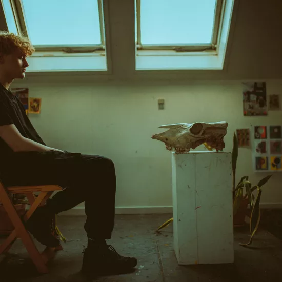 Man Sitting on a Chair in front of an Animal Skull