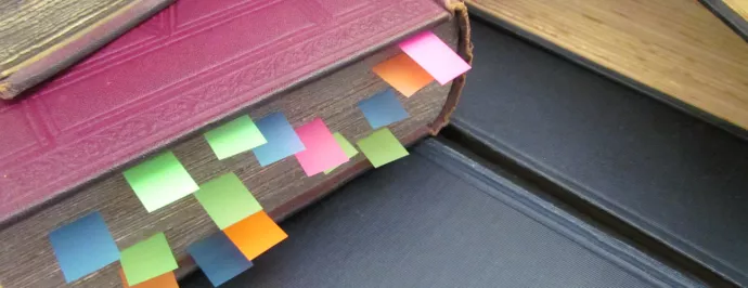 Photo of a text book with multiple post it flags.