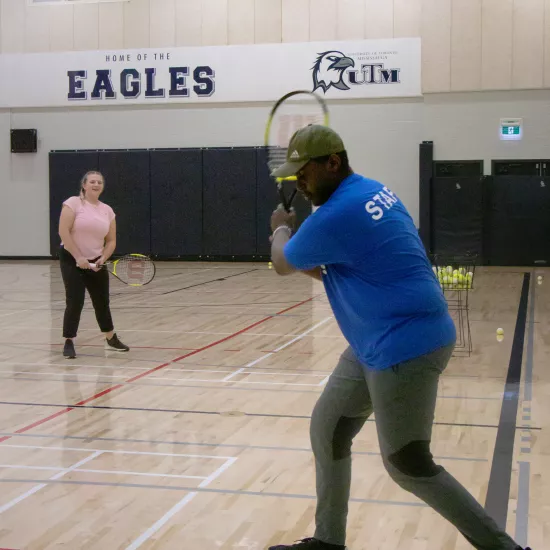 Learn to play instructor showing how to swing a tennis racquet 