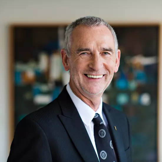 Ian Orchard smiling in a black suit with a white dress shirt and polka dot patterened tie 