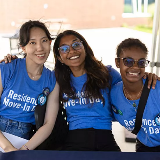 Three people wearing blue shirts hugging sitting down