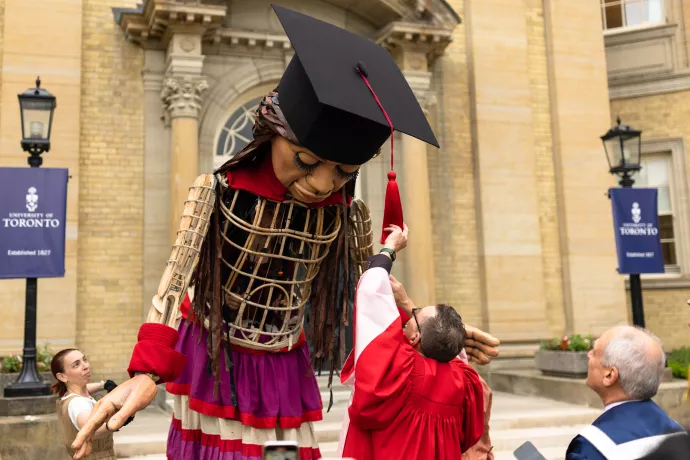 Little Amal has her mortarboard tassel adjusted outside Convocation Hall