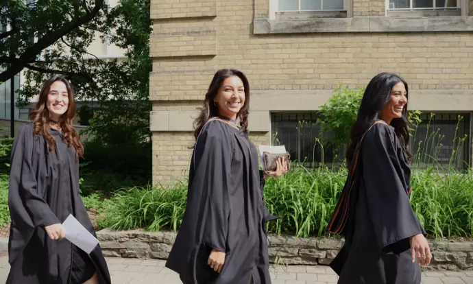 Three IMI grads walk into convocation hall. 