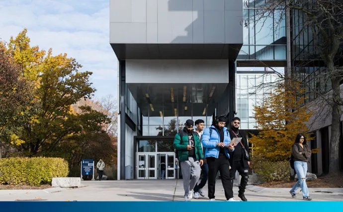 Five people walking through a beautiful fall campus