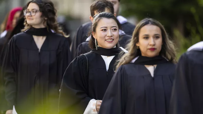 Four graduates in black robes line up for convocation