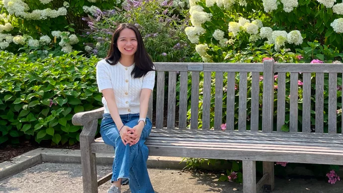 Minh Thuy Phi sitting on a wooden bench in a park