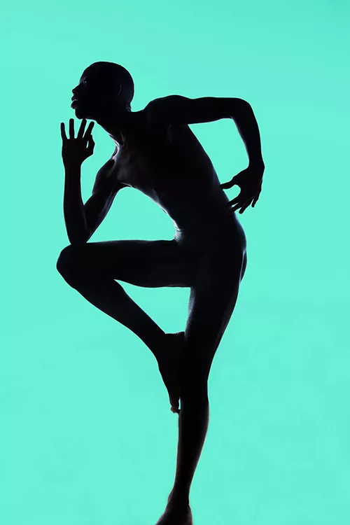 Full body silhouette of a male standing on one leg, bent over with one elbow on raised leg