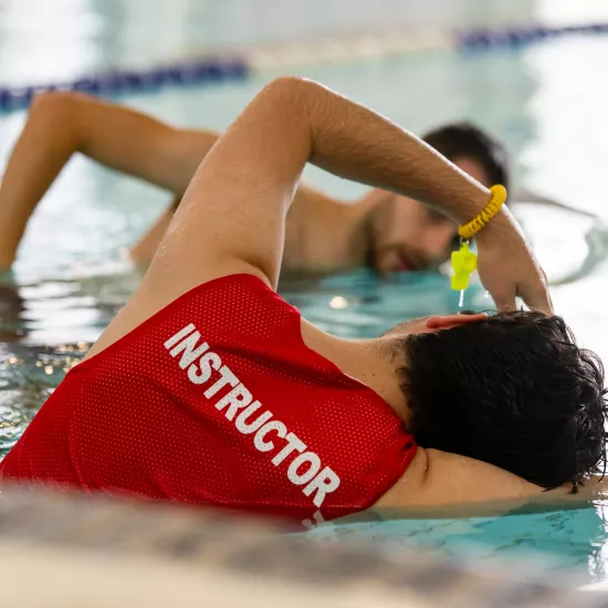 instructor shows a student how to swim