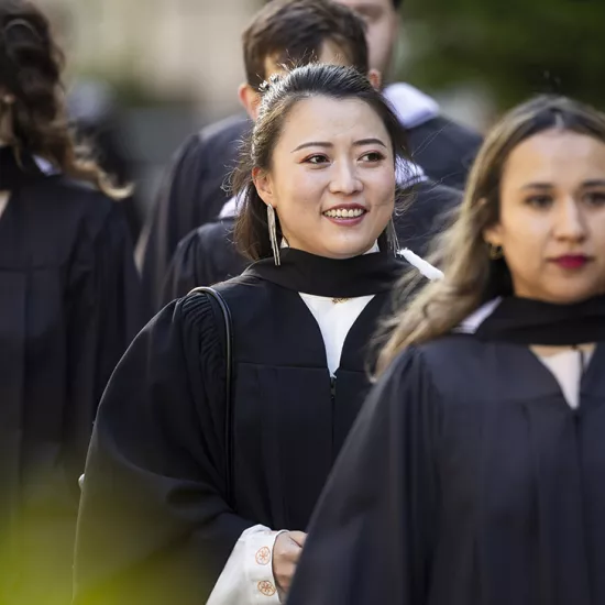 Four graduates in black robes line up for convocation