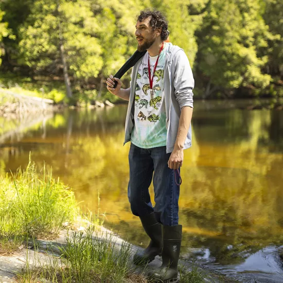 Man standing in front of a lake in summer.