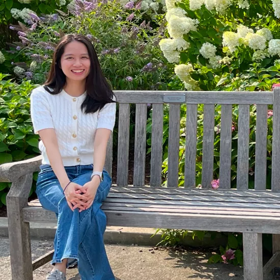 Minh Thuy Phi sitting on a wooden bench in a park