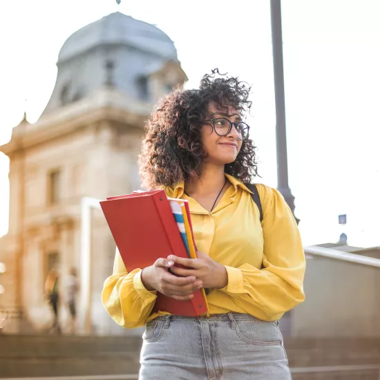 Student holding book outside architecture