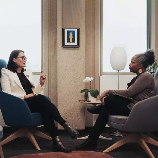 Alex Gillespie and Heather Hines seated in chairs by two windows